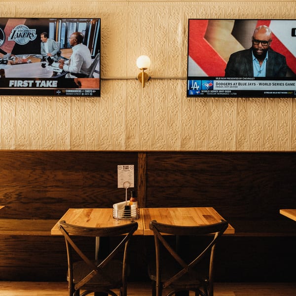 Elsie Lane Huntington interior with wooden tables, chairs, and two TVs displaying sports.